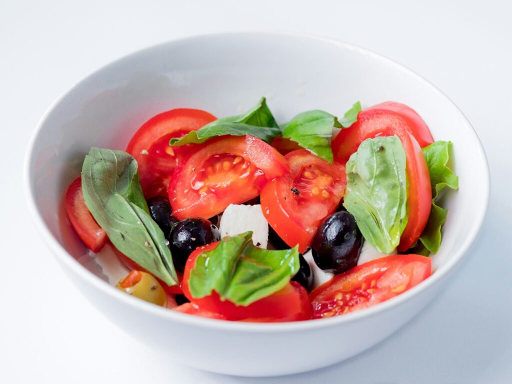 taça com salada fresca de tomate, folhas verdes e azeitonas pretas
